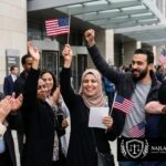 Attorney Najla sitting at her office desk in June 2026, smiling and holding an official U.S. immigration document regarding a nationwide case update.